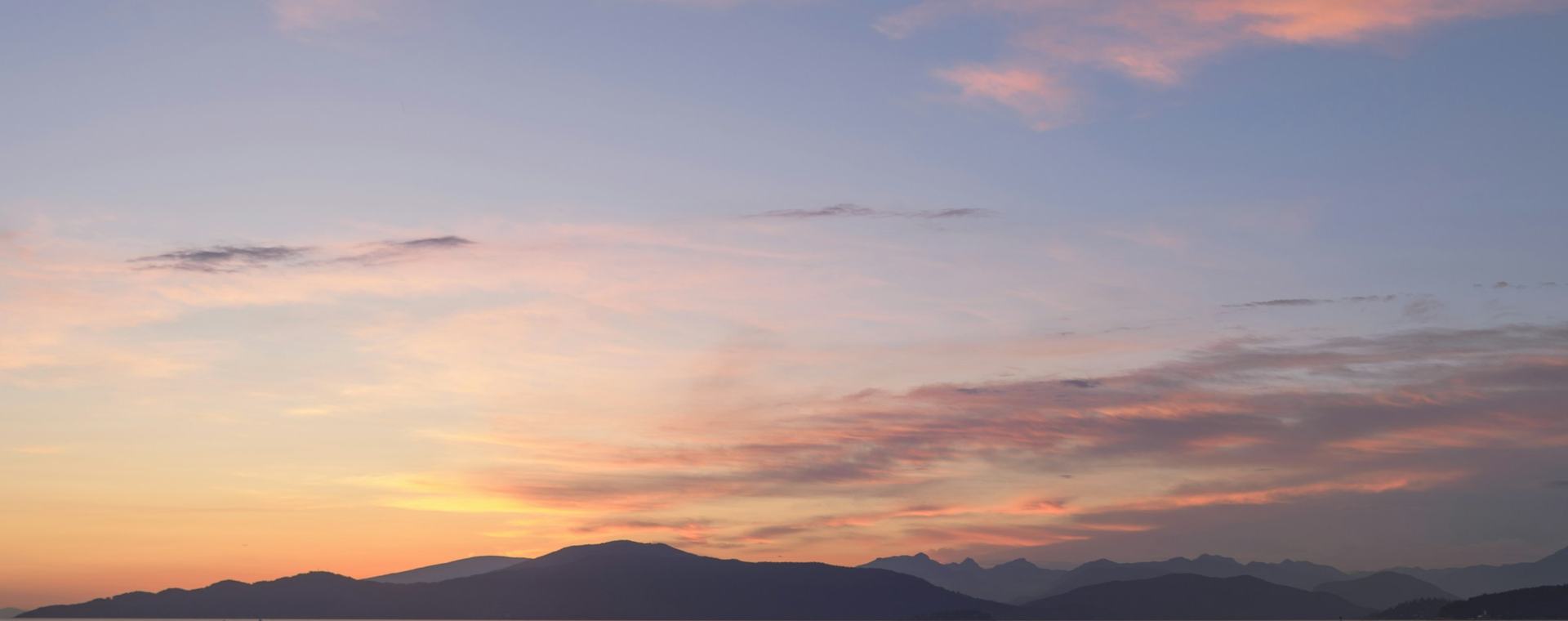 A pink and gold sunset sky above a mountain ridgeline near Vancouver